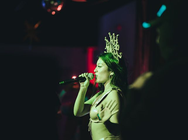 Performer in a Medusa headpiece singing on stage