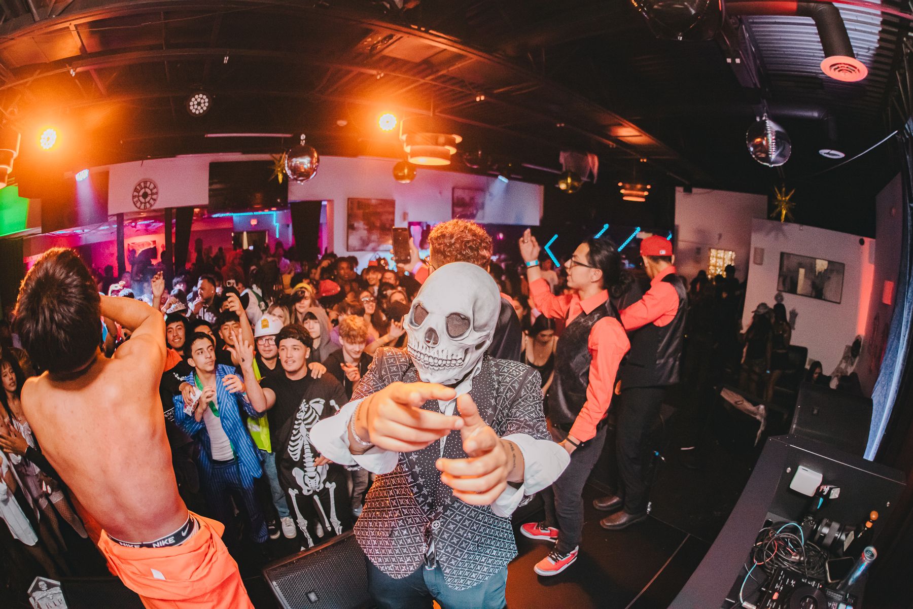 Masked entertainer on stage in front of a packed costumed crowd